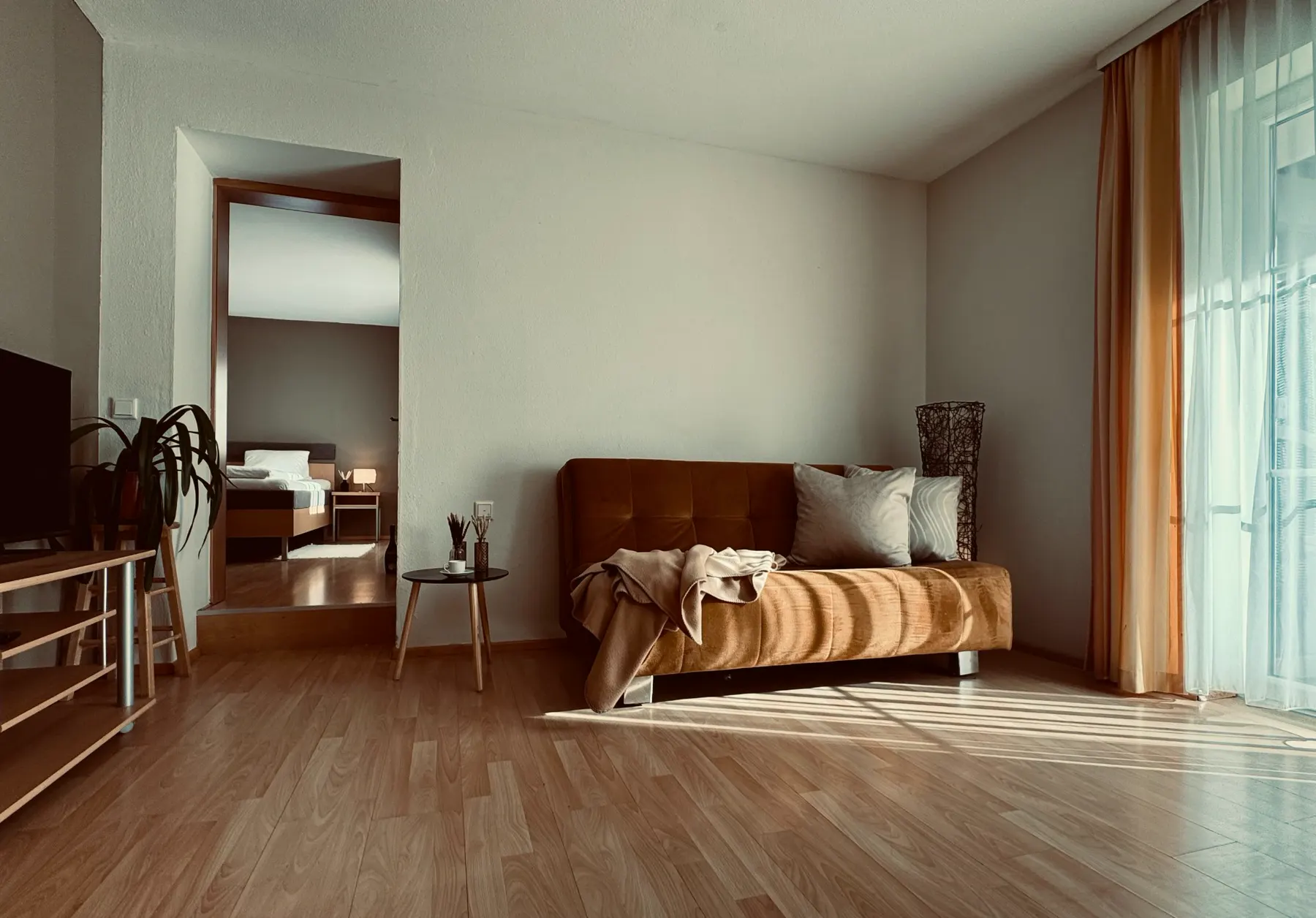Wohnzimmer mit Sofa und Blick ins Schlafzimmer